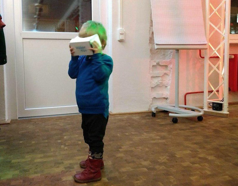 Hier ist ein vierjähriger Junge mit Cardboard zu sehen, der sich ein 360°-Video zum Beruf Dachdecker*in anschaut